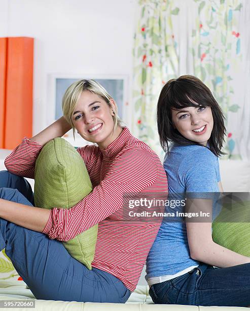 two young women sitting back to back - woman back pillow blonde stock pictures, royalty-free photos & images