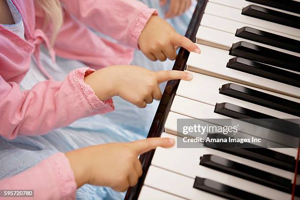 close-up of triplets playing piano - triplets identical stock pictures, royalty-free photos & images