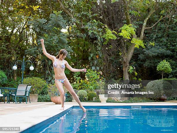 woman dipping toe in swimming pool - laughing teen stockfoto's en -beelden