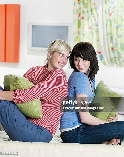 two young women sitting back to back - woman back pillow blonde stock pictures, royalty-free photos & images
