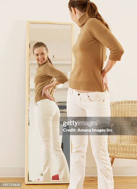 mid-adult trying on jeans - woman-looking-into-mirror-full-body stock pictures, royalty-free photos & images