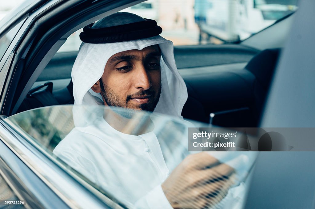 Emirati Businessman with smart phone in a car