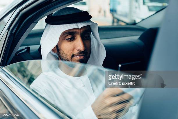 emirati businessman with smart phone in a car - arab and mobile stock pictures, royalty-free photos & images