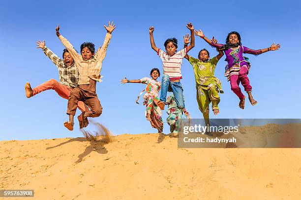 gruppe von glücklich indischen kinder springen sie in den sand dune - rajasthani youth stock-fotos und bilder