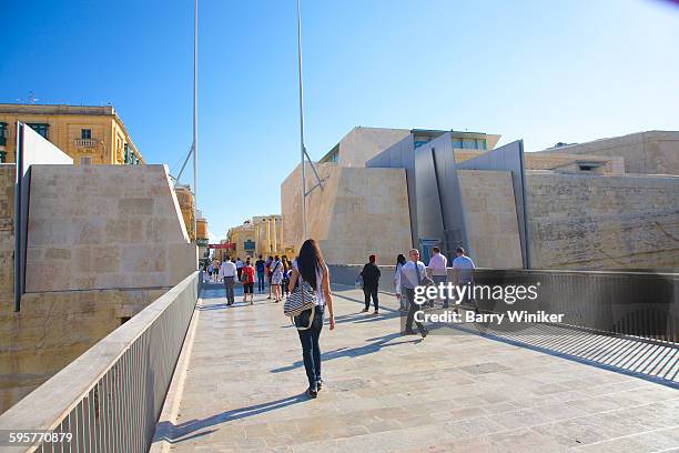 people crossing city gate on stone walkway, malta - city gate stock pictures, royalty-free photos & images