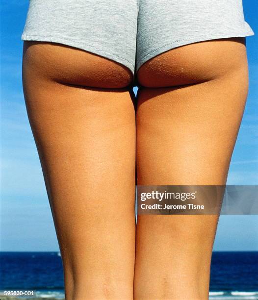 bottom and thighs of young woman wearing shorts, rear view, close-up - hot pants arsch stock-fotos und bilder