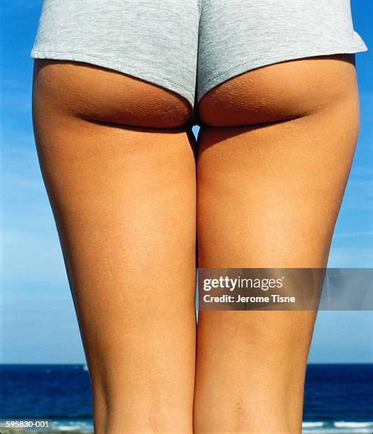 bottom and thighs of young woman wearing shorts, rear view, close-up - hot pants stock-fotos und bilder