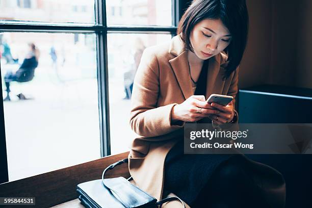 Businesswoman using cell phone in library