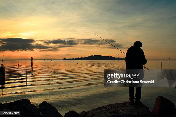 fisherman on the shore of lake trasimeno - lac trasimeno photos et images de collection