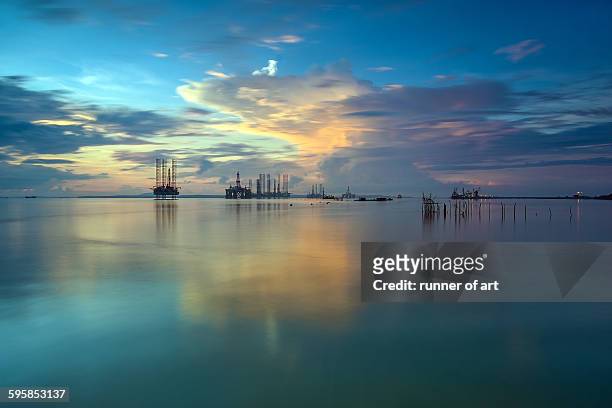 dancing clouds and silhouette drilling rig - oil production platform stock pictures, royalty-free photos & images