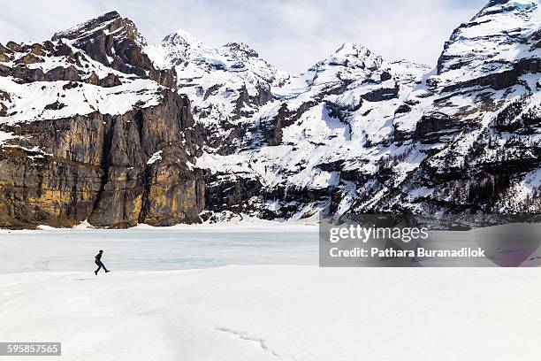 a man jumping on frozen lake - lac-oeschinensee photos et images de collection