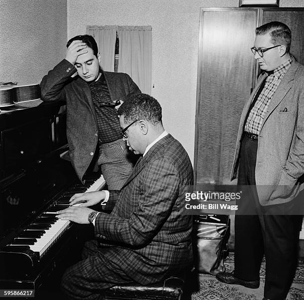 Argentine pianist, composer and arranger Lalo Schifrin and American drummer Mel Lewis listen to American jazz trumpeter Dizzy Gillespie on the piano,...