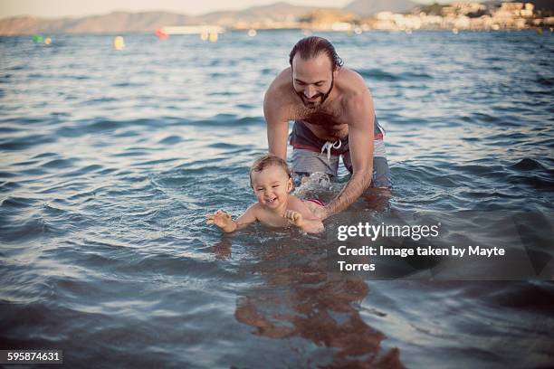 dad teaching baby to swim - babyschwimmen stock-fotos und bilder