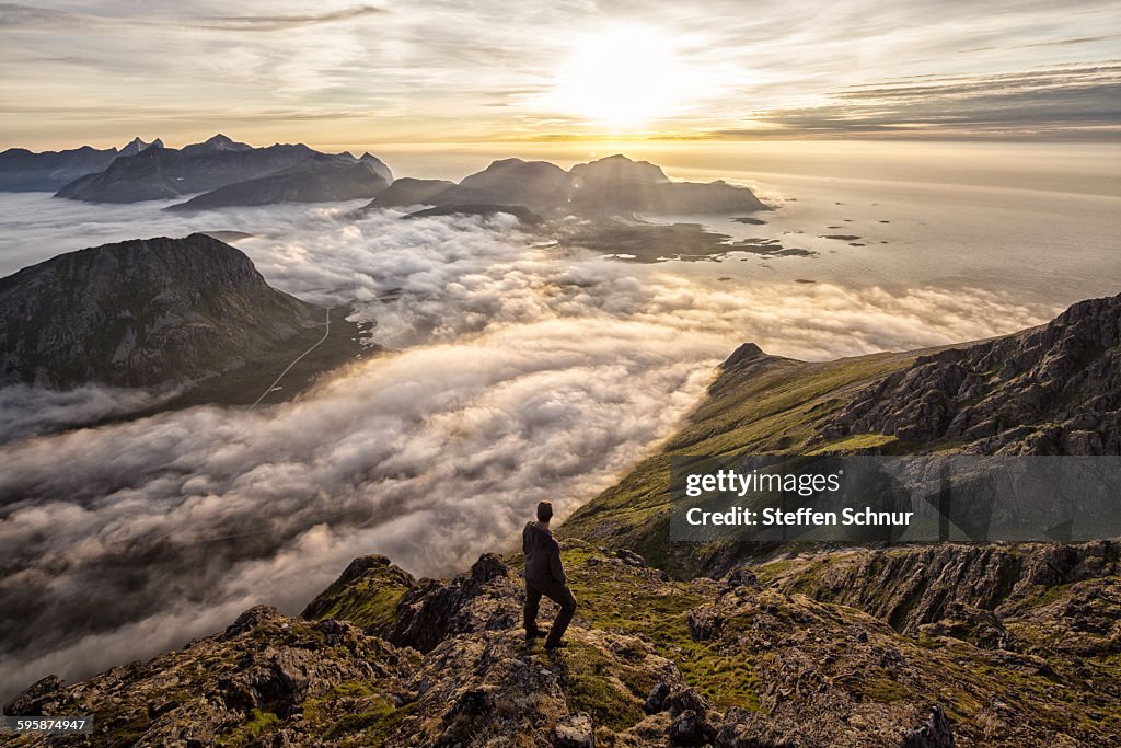 Man above the clouds on mountain Lofoten Norway