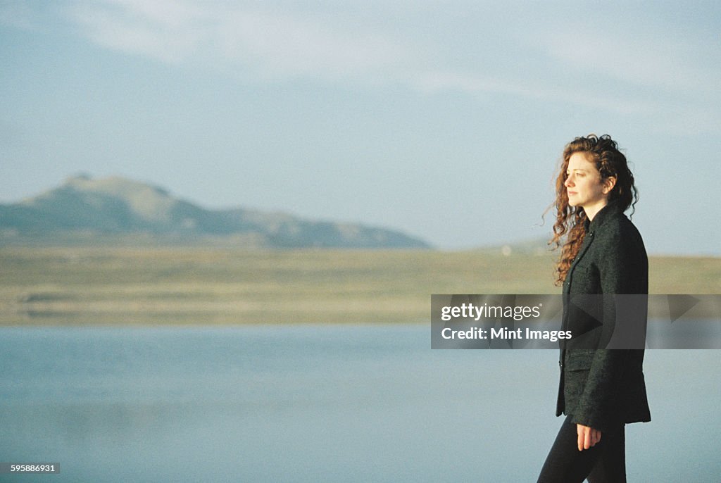 A woman standing on the shore of a lake.