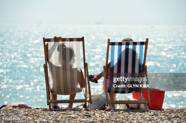 People sunbathe on Brighton Beach, southern England on August 26, 2016. Five beachgoers on Camber Sands beach on the south coast died as Britain...