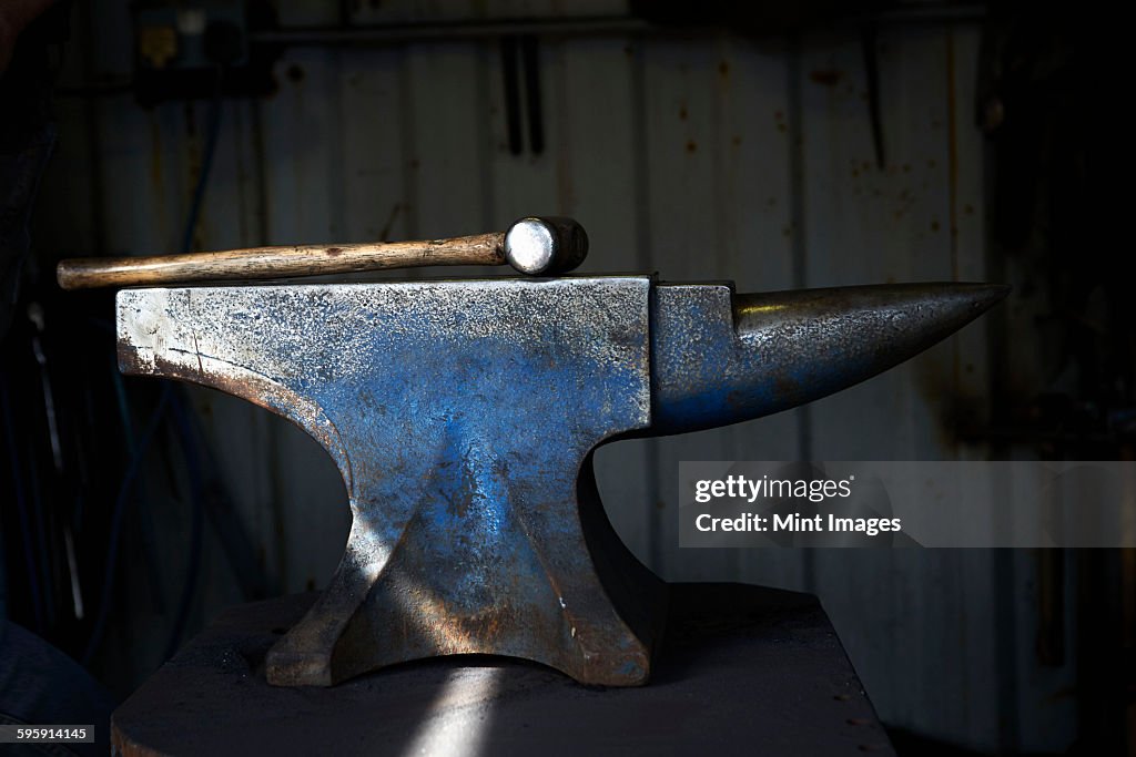 Hammer lying on an iron anvil in a traditional blacksmiths forge.