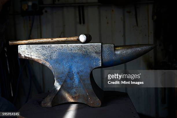 hammer lying on an iron anvil in a traditional blacksmiths forge. - anvil stock pictures, royalty-free photos & images