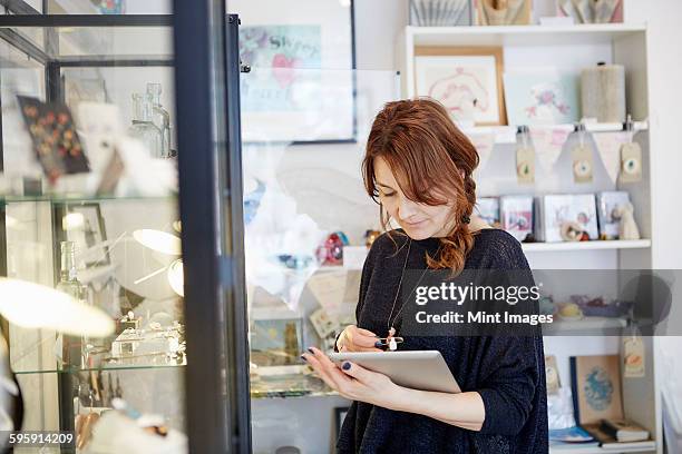 a mature woman using a digital tablet, using the touch screen, stock-taking in a small gift shop.  - gift shop ストックフォトと画像