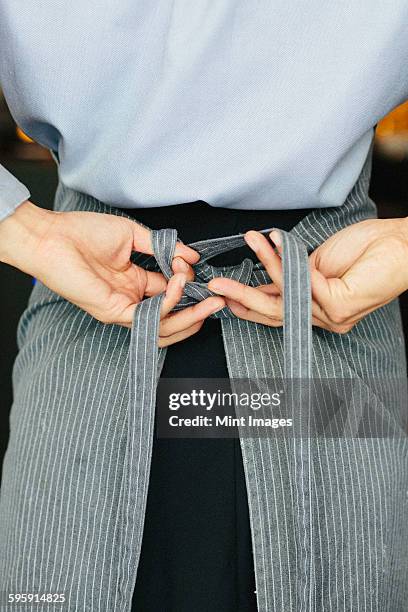 young waitress tying her apron at a city restaurant. - apron stock pictures, royalty-free photos & images