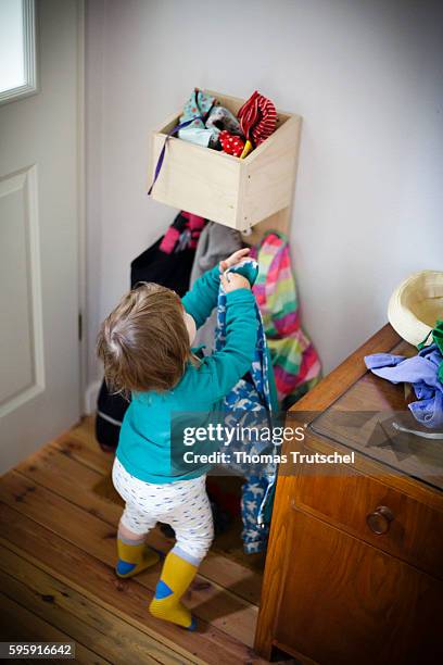 Berlin, Germany A toddler hangs up a jacket on a coat rack on August 11, 2016 in Berlin, Germany.