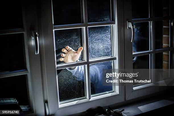 Berlin, Germany Staged photo about burglary. A man posing on a house window with a flashlight on August 11, 2016 in Berlin, Germany.