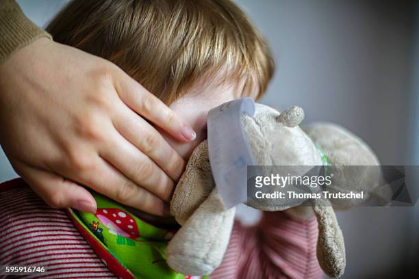 Berlin, Germany A toddler is hiding his face behind a stuffed toy while her mother runs her hand over his face on August 12, 2016 in Berlin, Germany.