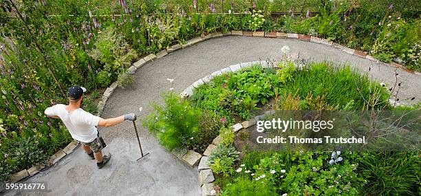 Berlin, Germany Staged Photo: A man builds a path in his garden and rakes gravel on August 12, 2016 in Berlin, Germany.