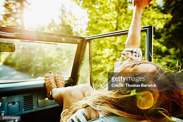 woman riding in passenger seat of convertible - wochenendaktivität stock-fotos und bilder