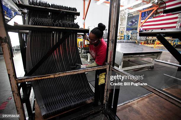 Fiat Chrysler Automobiles worker handles a part that came off the press at the FCA Sterling Stamping Plant August 26, 2016 in Sterling Heights,...