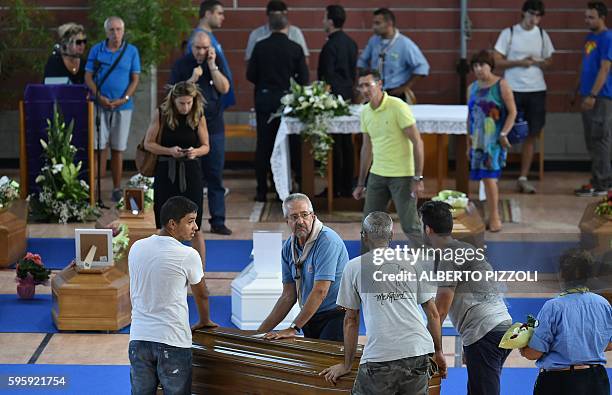 People and Italian scouts help to carry coffins of earthquake victims, in a gymnasium arranged in a chapel of rest on August 26 in Ascoli Piceno, two...