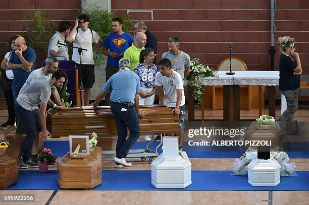 People carry coffins of earthquake victims, in a gymnasium arranged in a chapel of rest on August 26 in Ascoli Piceno, two day after a 6.2-magnitude...