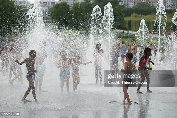 Children cooling off in Parc Andre Citroen during a summer heat wave on August 26, 2016 in Paris, France. The temperature reached 100 fahrenheit...