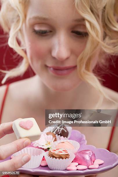 young woman eating chocolates and sweets - petit four bildbanksfoton och bilder