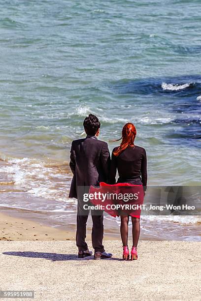 a man and a woman flapping skirt on the beach - skirt blowing stock pictures, royalty-free photos & images