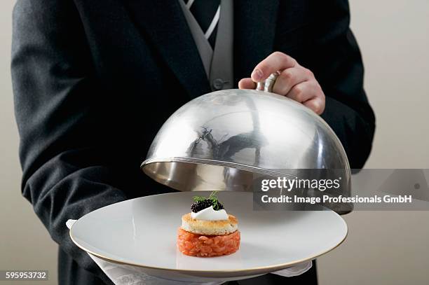 butler serving salmon tartare on plate with domed cover - glocke stock-fotos und bilder