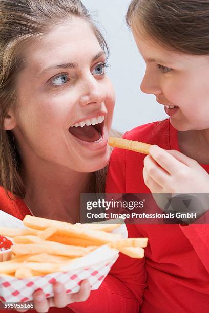 young woman and girl eating chips together - family eating potato chips imagens e fotografias de stock