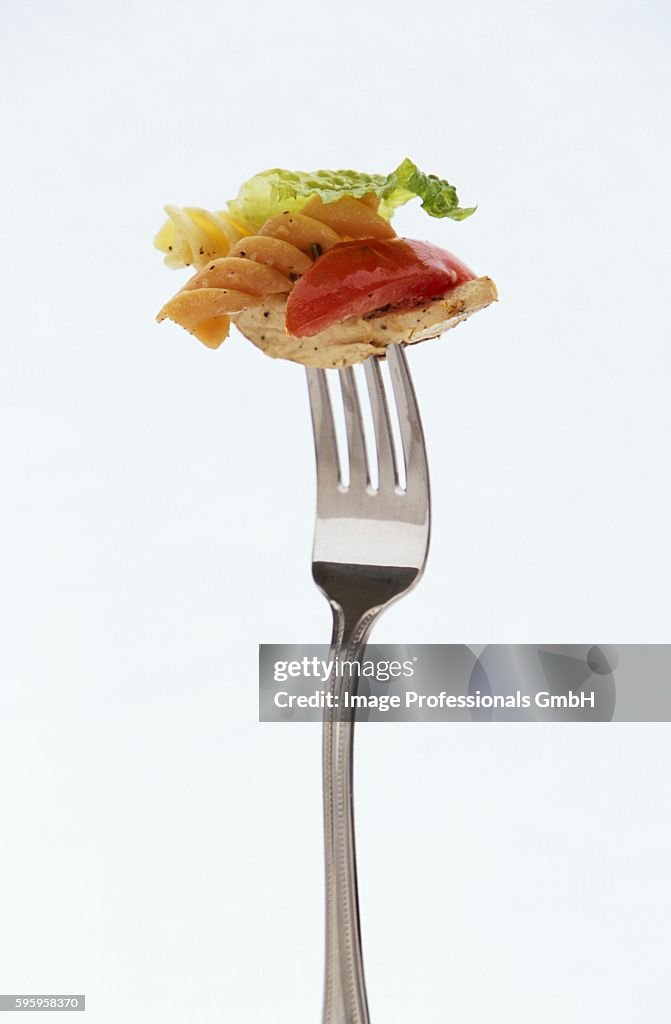 Pasta salad with chicken on fork