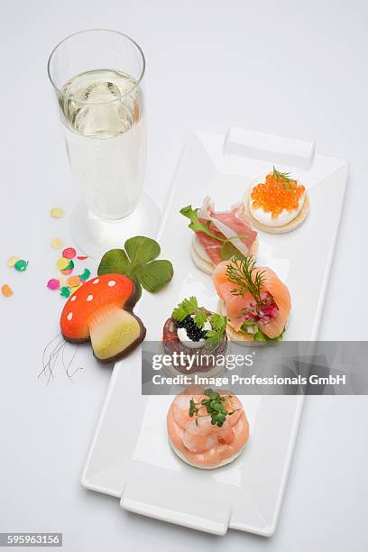 canap??s, glass of sparkling wine, good luck charms for new year - canap�� stock pictures, royalty-free photos & images