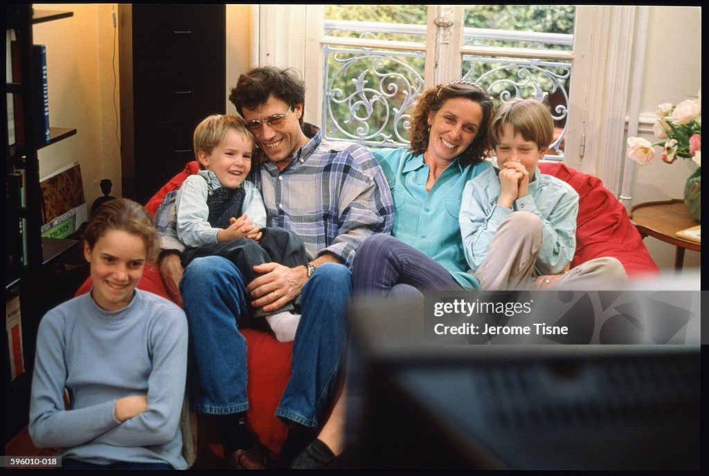 Parents sitting with three children (5-12) in front of television