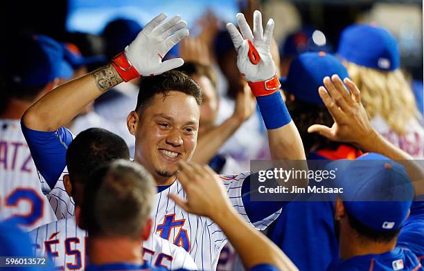 Wilmer Flores of the New York Mets celebrates his fifth inning grand slam home run against the Philadelphia Phillies with his teammates in the dugout...