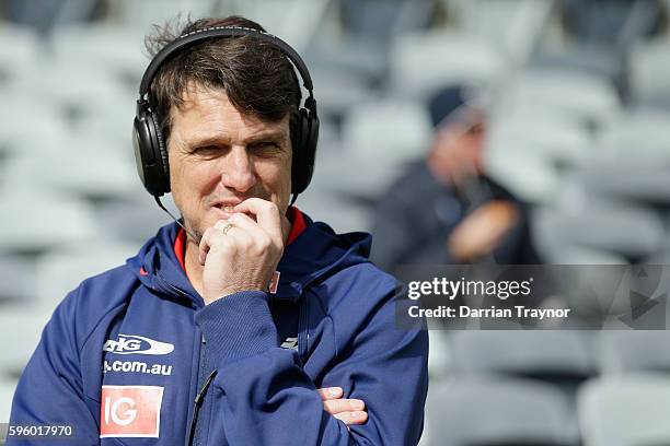 Paul Roos, Senior Coach of the Demons does a radio interview before the round 23 AFL match between the Geelong Cats and the Melbourne Demons at...