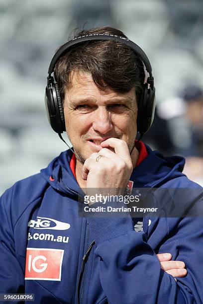 Paul Roos, Senior Coach of the Demons does a radio interview before the round 23 AFL match between the Geelong Cats and the Melbourne Demons at...