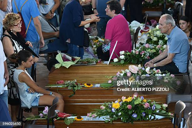 Relatives of earthquake victims sit next to coffins, in a gymnasium arranged in a chapel of rest on August 27 in Ascoli Piceno, three days after a...