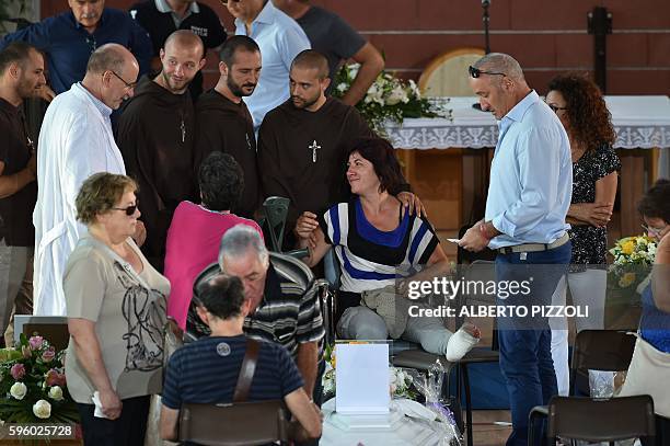 Relatives of earthquake victims gather next to the coffins, in a gymnasium arranged in a chapel of rest on August 27 in Ascoli Piceno, three days...