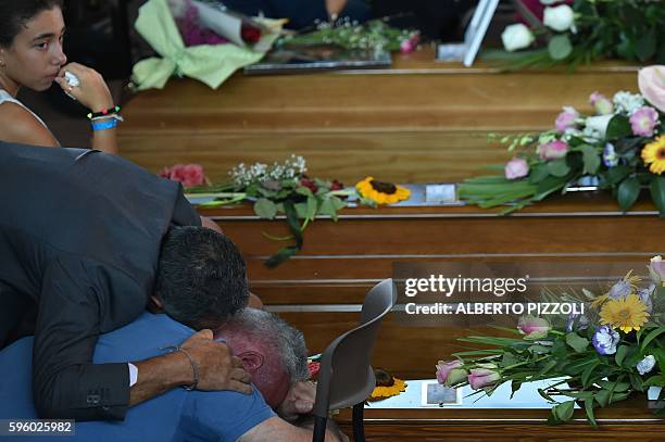 Men mourn next to the coffin of an earthquake victim, in a gymnasium arranged in a chapel of rest on August 27 in Ascoli Piceno, three days after a...