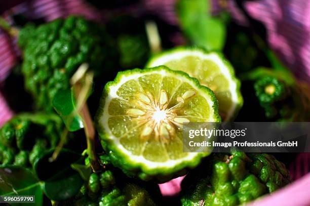thai limes with wrinkled skin, whole and halved - thai fruit carving stock pictures, royalty-free photos & images