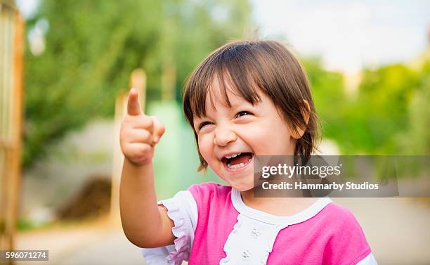 portrait of laughing baby girl pointing somewhere with content s - baby hands pointing stock pictures, royalty-free photos & images