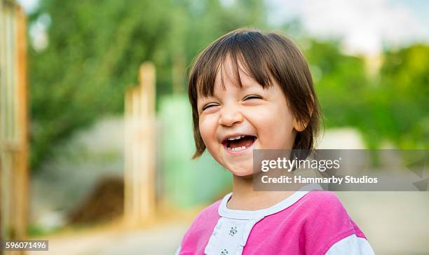 portrait of laughing baby girl with content smile - eenjarig plantenkenmerk stockfoto's en -beelden