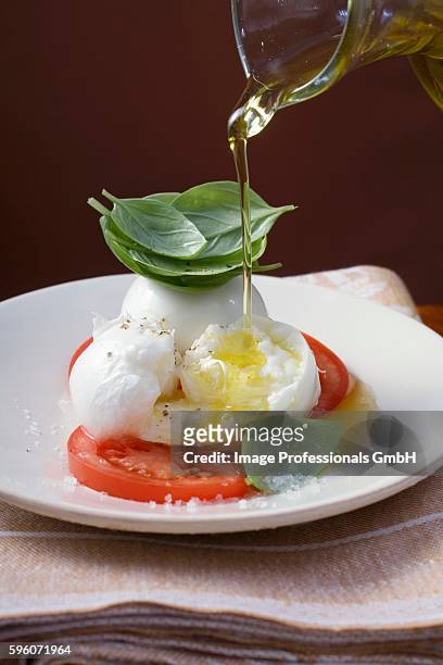 drizzling insalata caprese with olive oil - insalata stockfoto's en -beelden